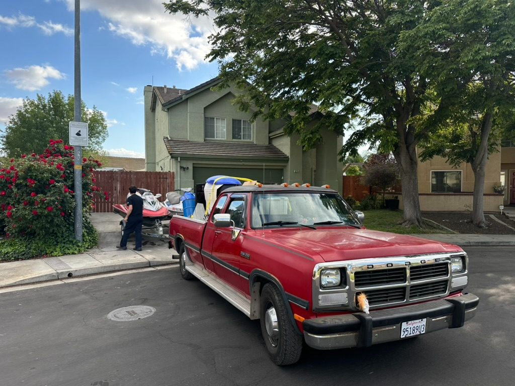 Hauling Patriots red Dodge pickup loaded with jet skis ready for delivery in a Nashville neighborhood