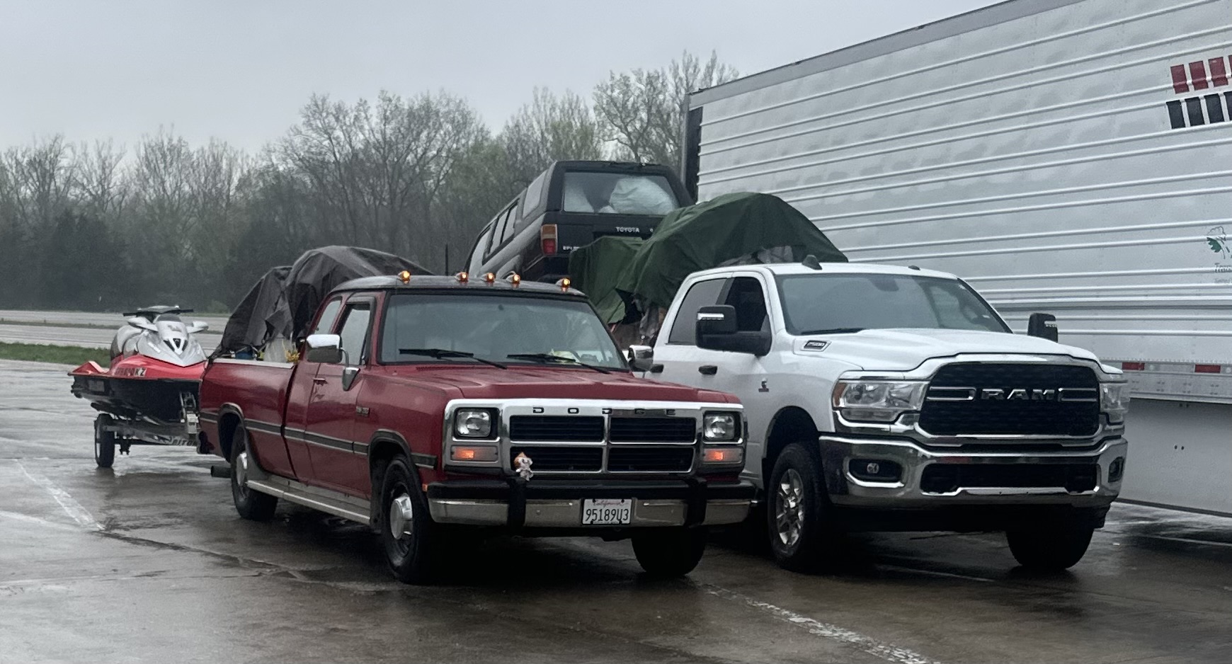Hauling Patriots red Dodge pickup and white Ram truck staged with a loaded trailer and a jet ski on a Nashville-area lot